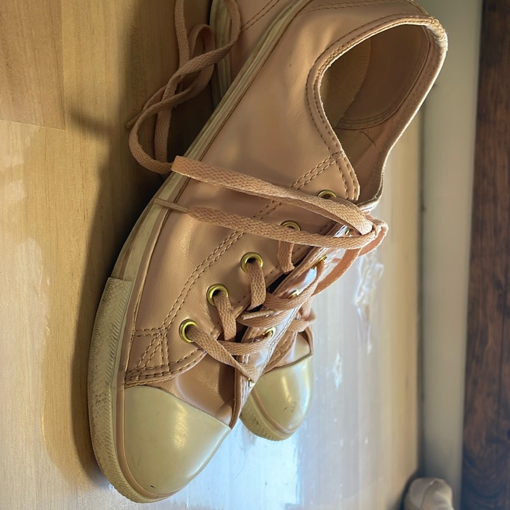 Converse All-Star, soft pink leather sneakers with gold embellishment.